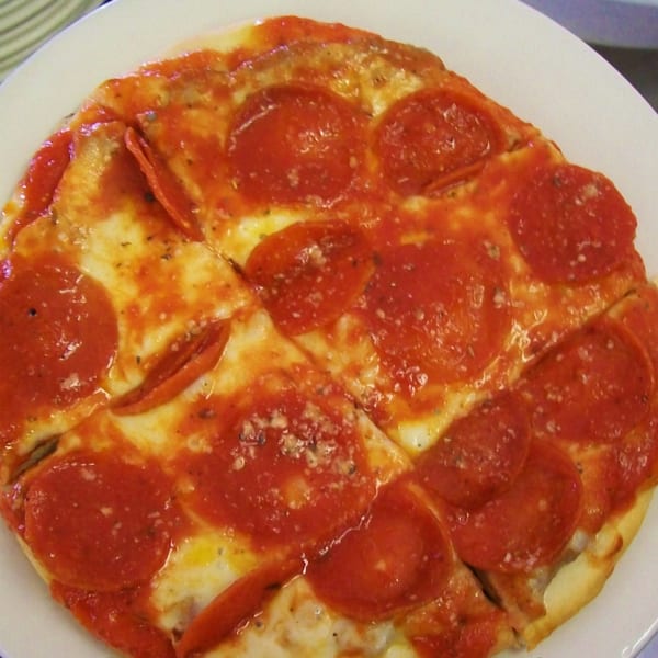 A small, round pepperoni pizza from Yetty's Pizza, sliced into six pieces on a white plate.